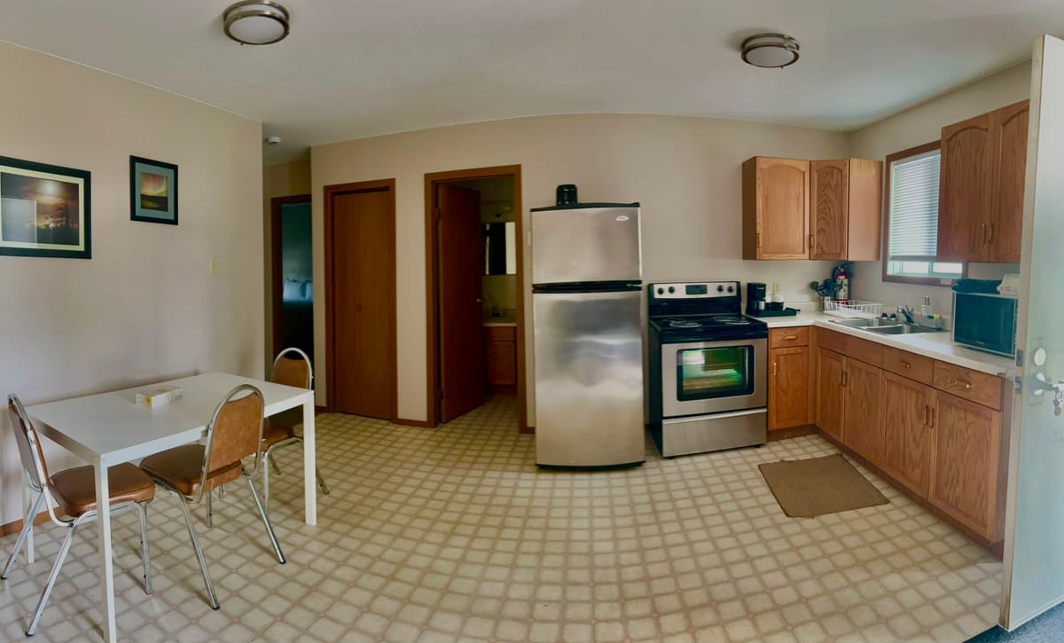 Full kitchen with stainless steel fridge, stove and a dining table in a Birch Grove apartment