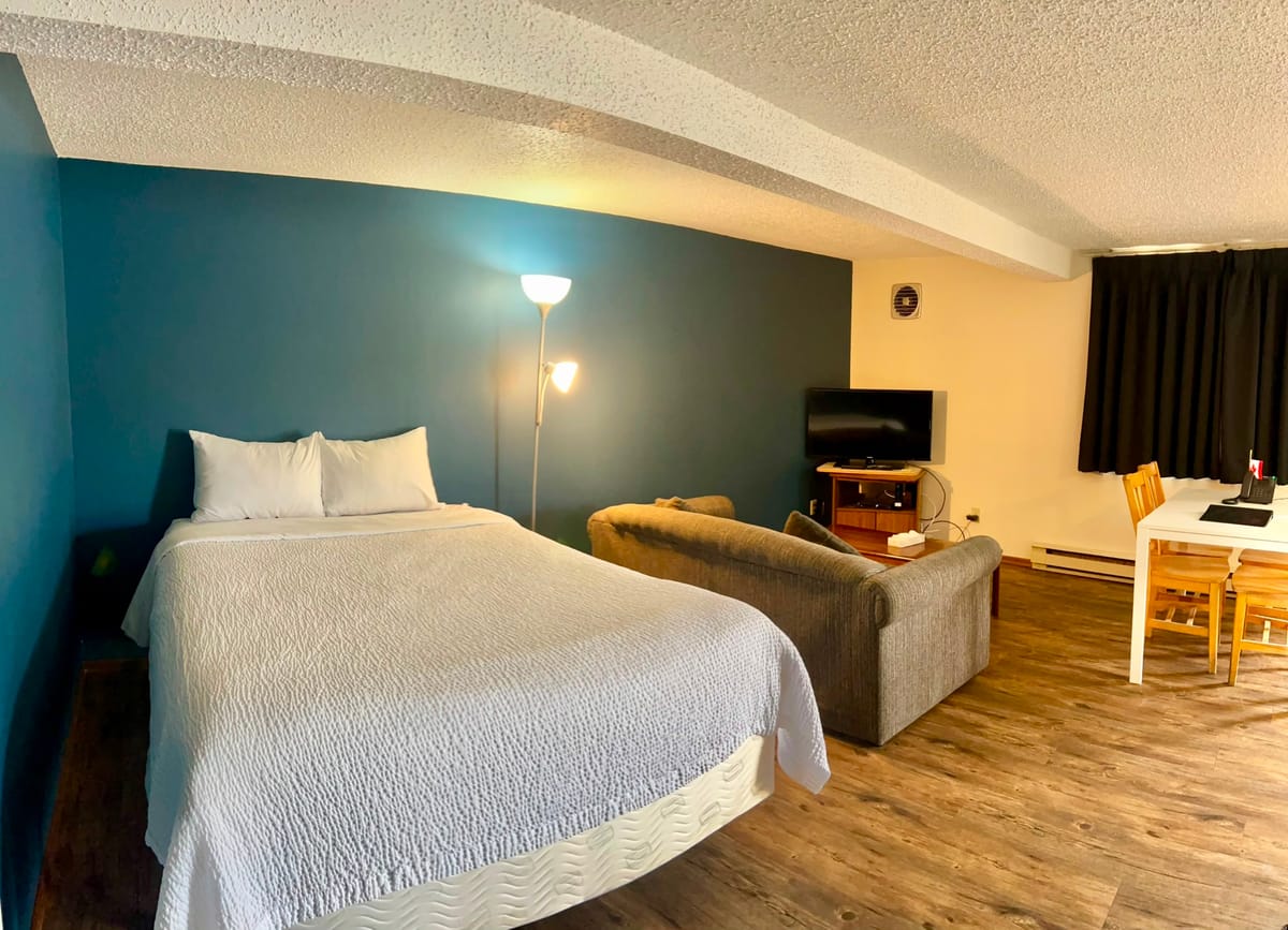 Open-plan bedroom with a queen bed, sofa and dining table in a 2 Queen Apartment with extra bed at Birch Grove