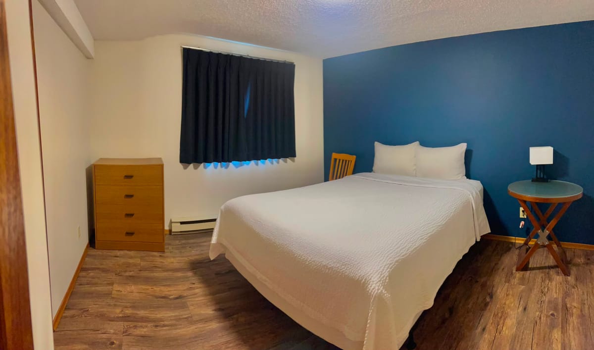 Queen bedroom with a blue accent wall in a Birch Grove apartment